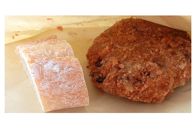 食べやすい大きさにカットされたバゲット（細長いフランスパン。バゲットは杖という意味）と、揚げたてのメンチカツが大接近。新しい惣菜メンチカツパン、メンチカツサンドのよう。この美味しそうな風景が商店街の物語『パンで街を幸せに』の表紙を飾ることになりました。
